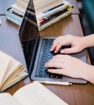 open books on table, student working on laptop, aerial shot