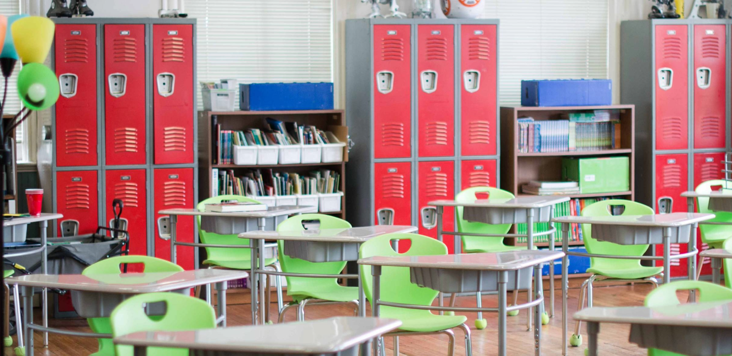 Empty classroom with desks, lockers, and bookshelves